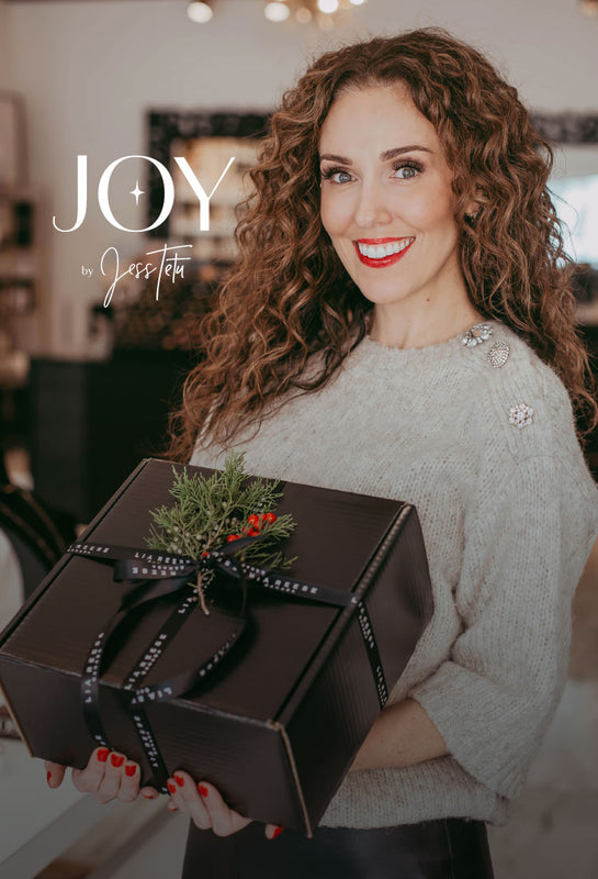 JOY by Jess Tetu Holiday Gift Box featuring a Lia Reese box decorated with greenery, held by Jess Tetu